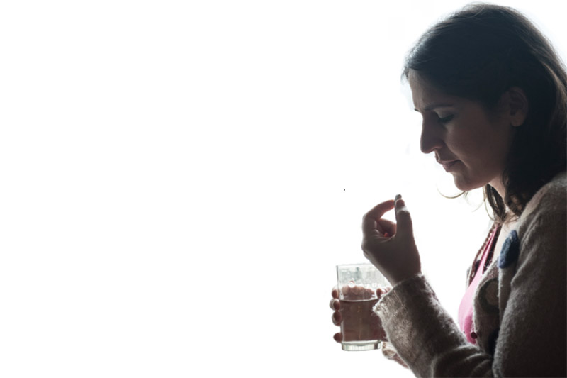 mujer tomando pastilla con vaso de agua en la mano