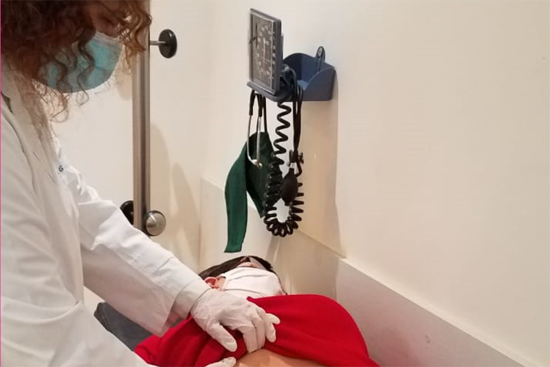 vista fotografia: doctora médica atendieno a paciente que se encuentra recostada sobre camilla